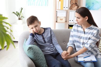 Photo of Child psychologist working with boy in office