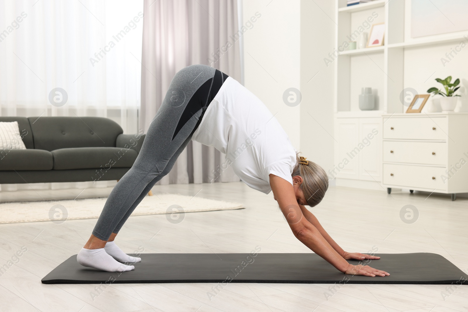 Photo of Senior woman practicing yoga on mat at home