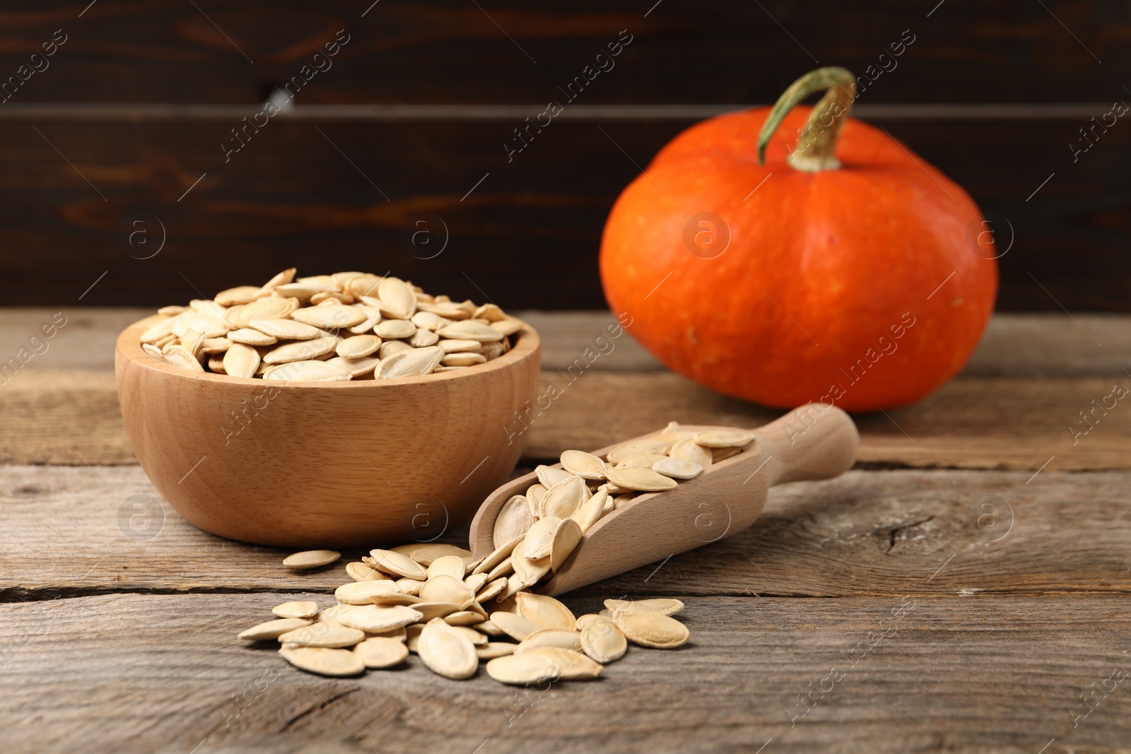 Photo of Bowl, scoop with seeds and fresh pumpkin on wooden table