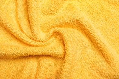 Photo of Crumpled orange microfiber cloth as background, closeup