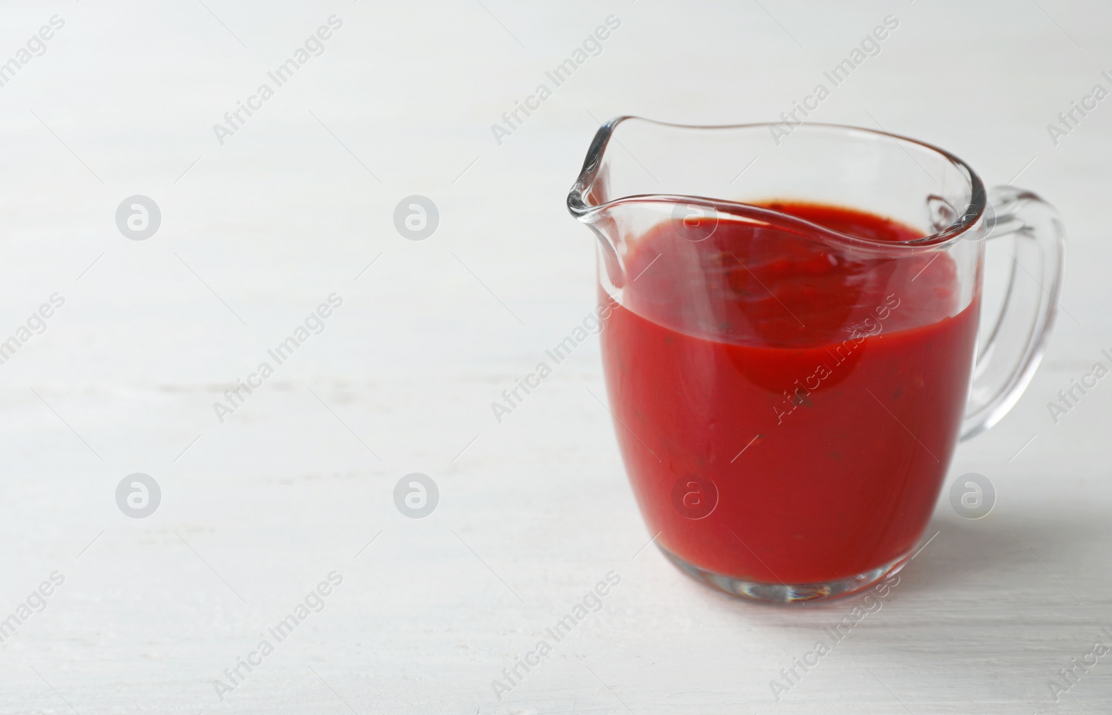 Photo of Jug with spicy chili sauce on light table