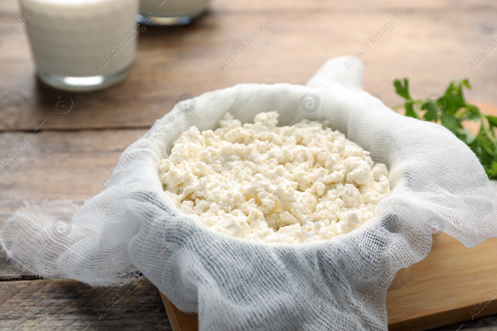 Photo of Delicious fresh cottage cheese with parsley on wooden table