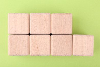 Photo of International Organization for Standardization. Wooden cubes with abbreviation ISO and number 9001 on light green background, flat lay