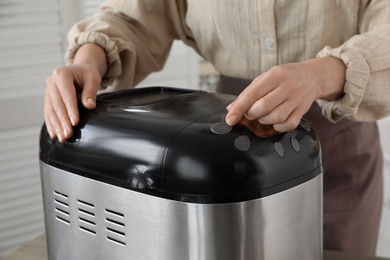 Woman using breadmaker machine in kitchen, closeup