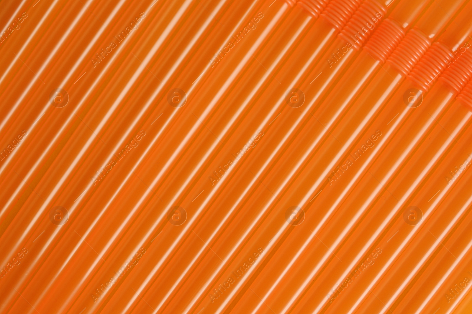 Photo of Many orange plastic drinking straws as background, closeup
