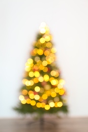 Blurred view of beautiful Christmas tree with fairy lights, indoors