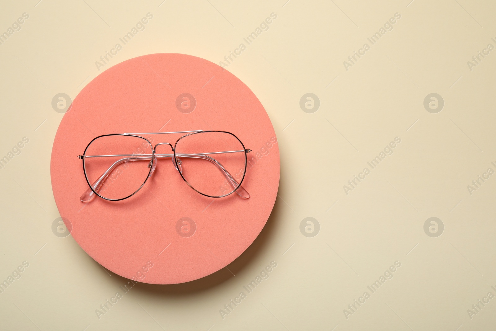 Photo of Stylish pair of glasses with metal frame on beige background, top view. Space for text