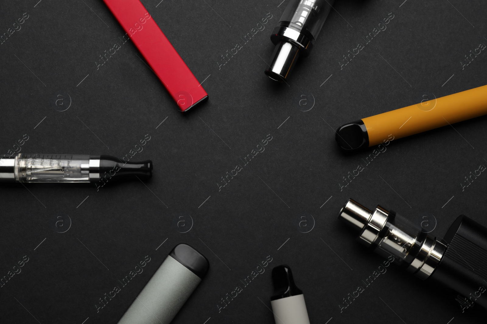 Photo of Many electronic smoking devices on black background, flat lay. Space for text