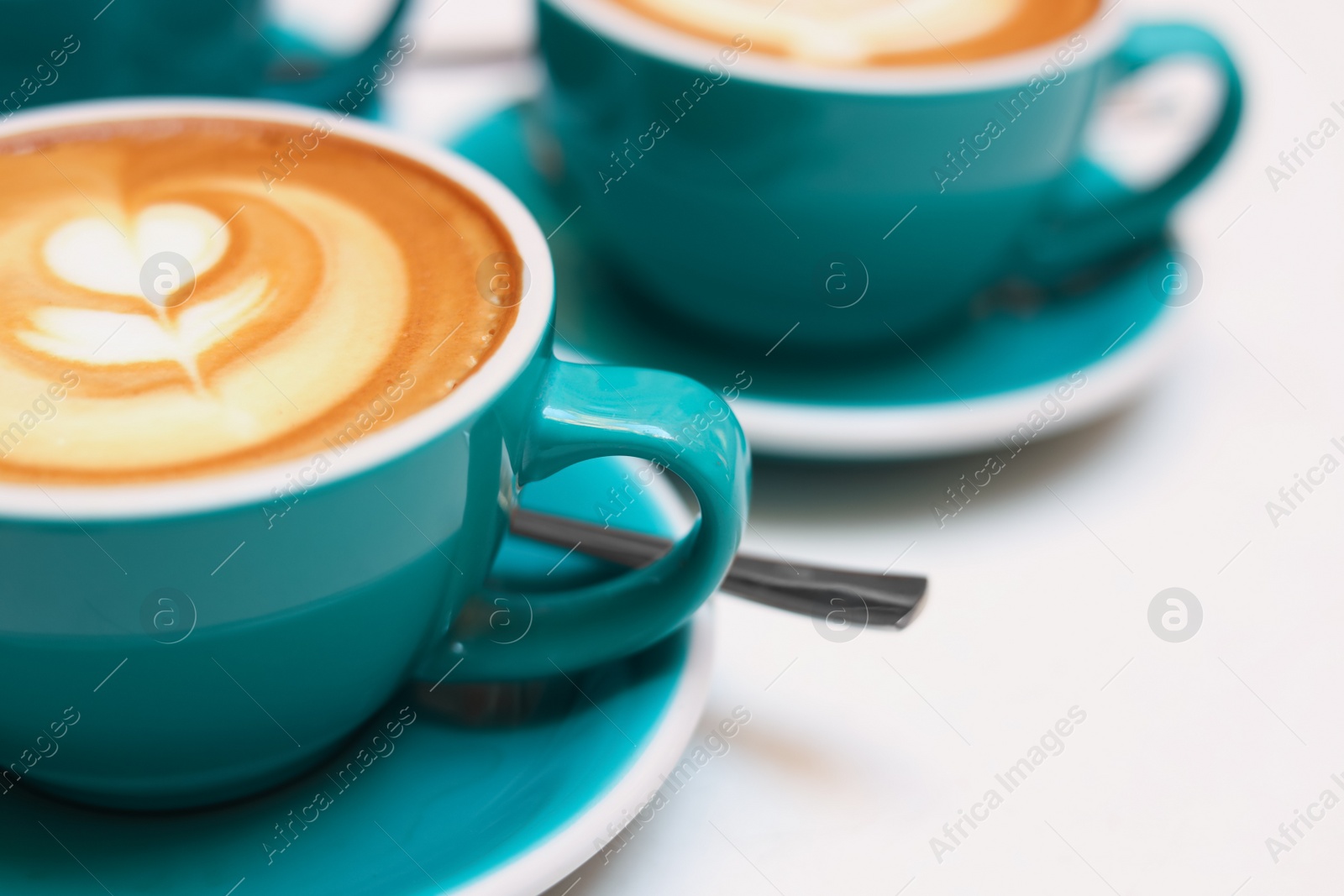 Photo of Cups of aromatic coffee on beige background, closeup