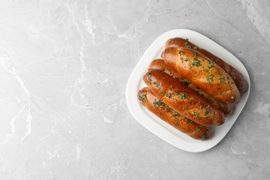 Photo of Plate of bread loaves with garlic and herbs on light table, top view. Space for text