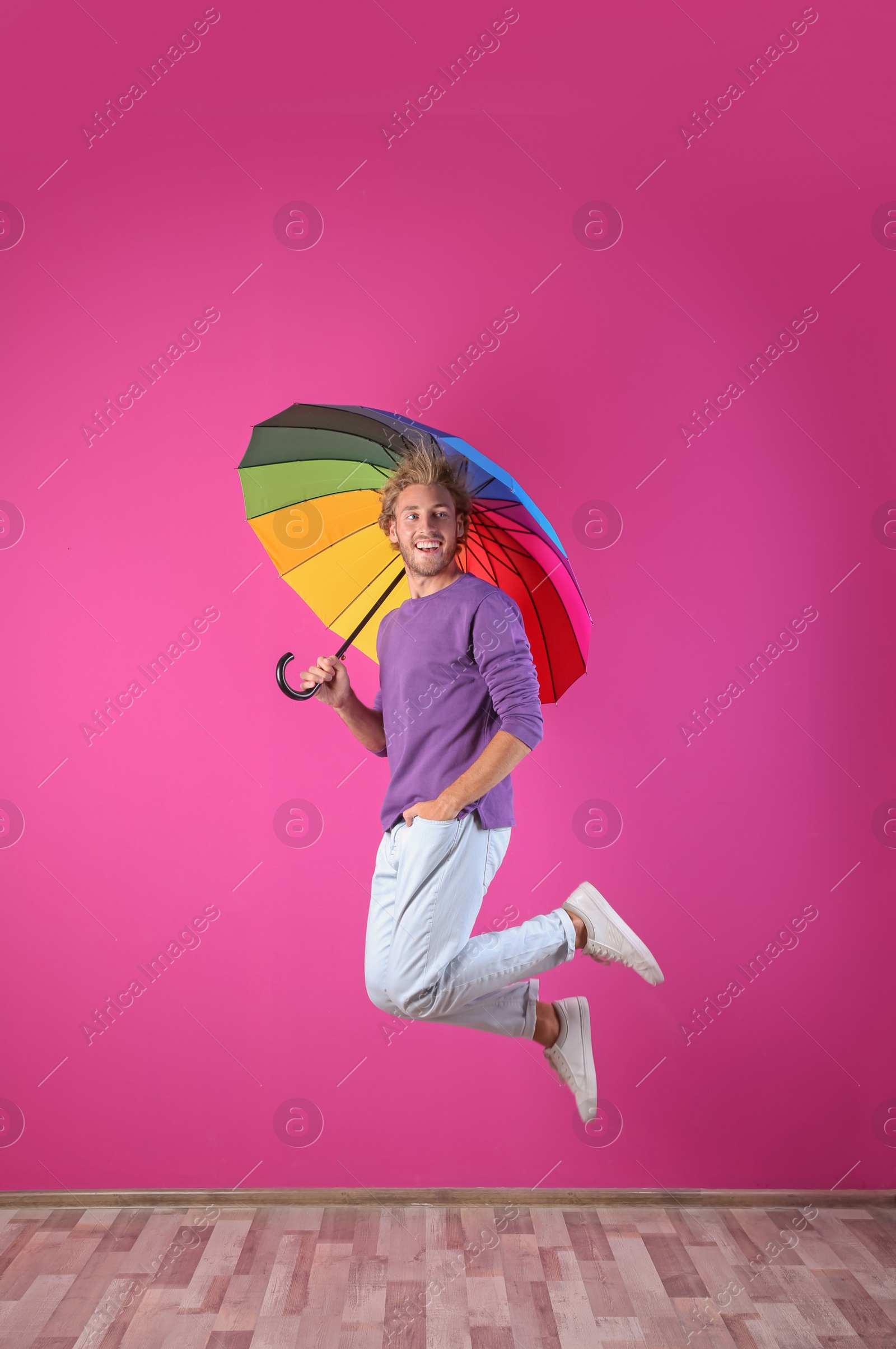 Photo of Man with rainbow umbrella near color wall