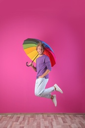 Photo of Man with rainbow umbrella near color wall