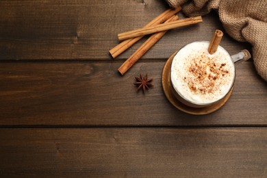 Cup of hot drink with whipped cream and aromatic cinnamon on wooden table, flat lay. Space for text
