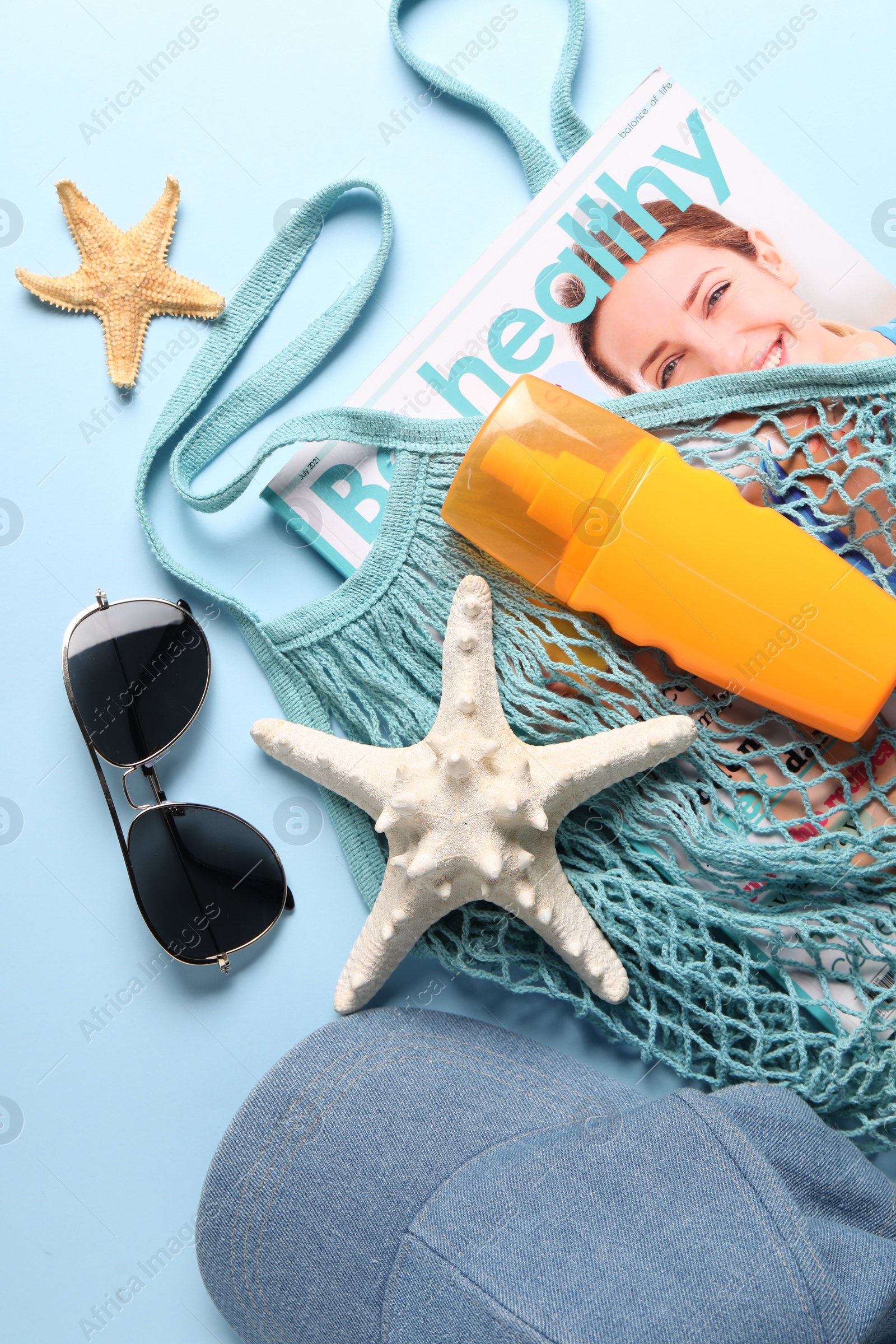 Photo of String bag and different beach accessories on light blue background, top view