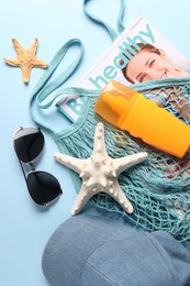 String bag and different beach accessories on light blue background, top view