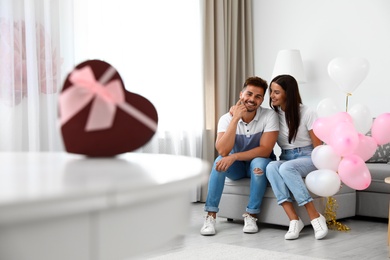 Photo of Young couple with air balloons at home. Celebration of Saint Valentine's Day