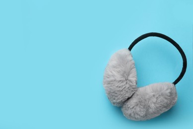Photo of Stylish warm earmuffs on light blue background, top view. Space for text