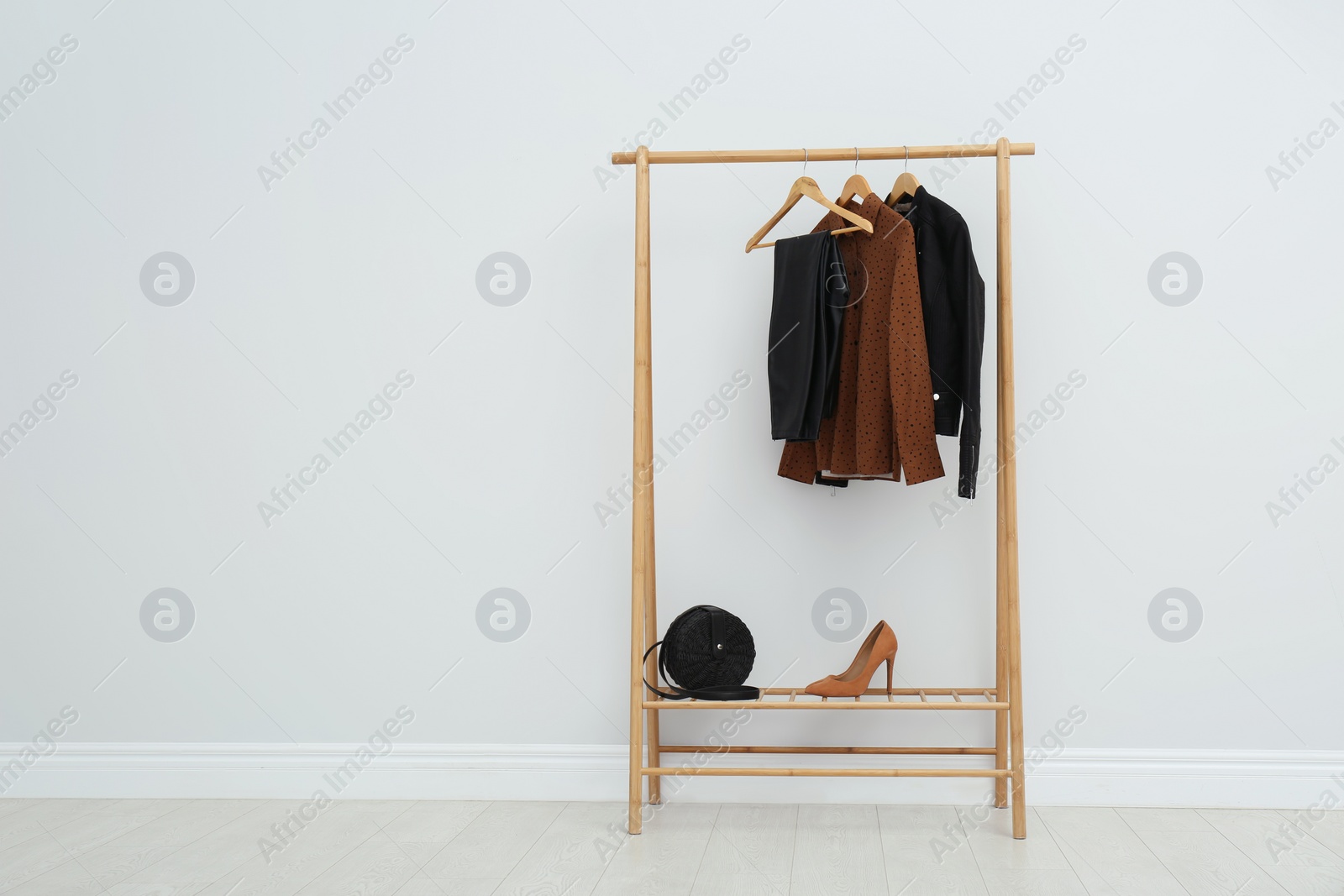 Photo of Wooden rack with stylish clothes in room. Space for text