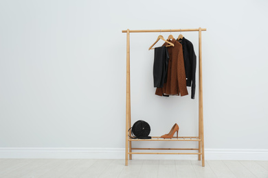 Wooden rack with stylish clothes in room. Space for text