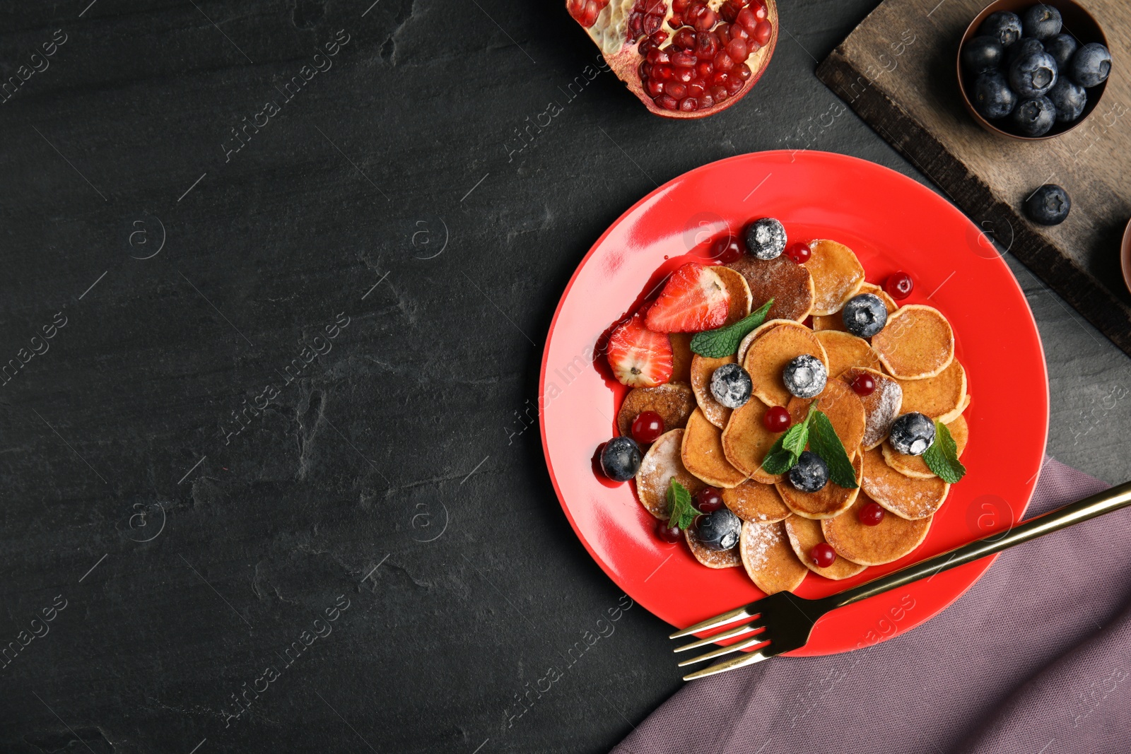 Photo of Cereal pancakes with berries and mint on black table, flat lay. Space for text