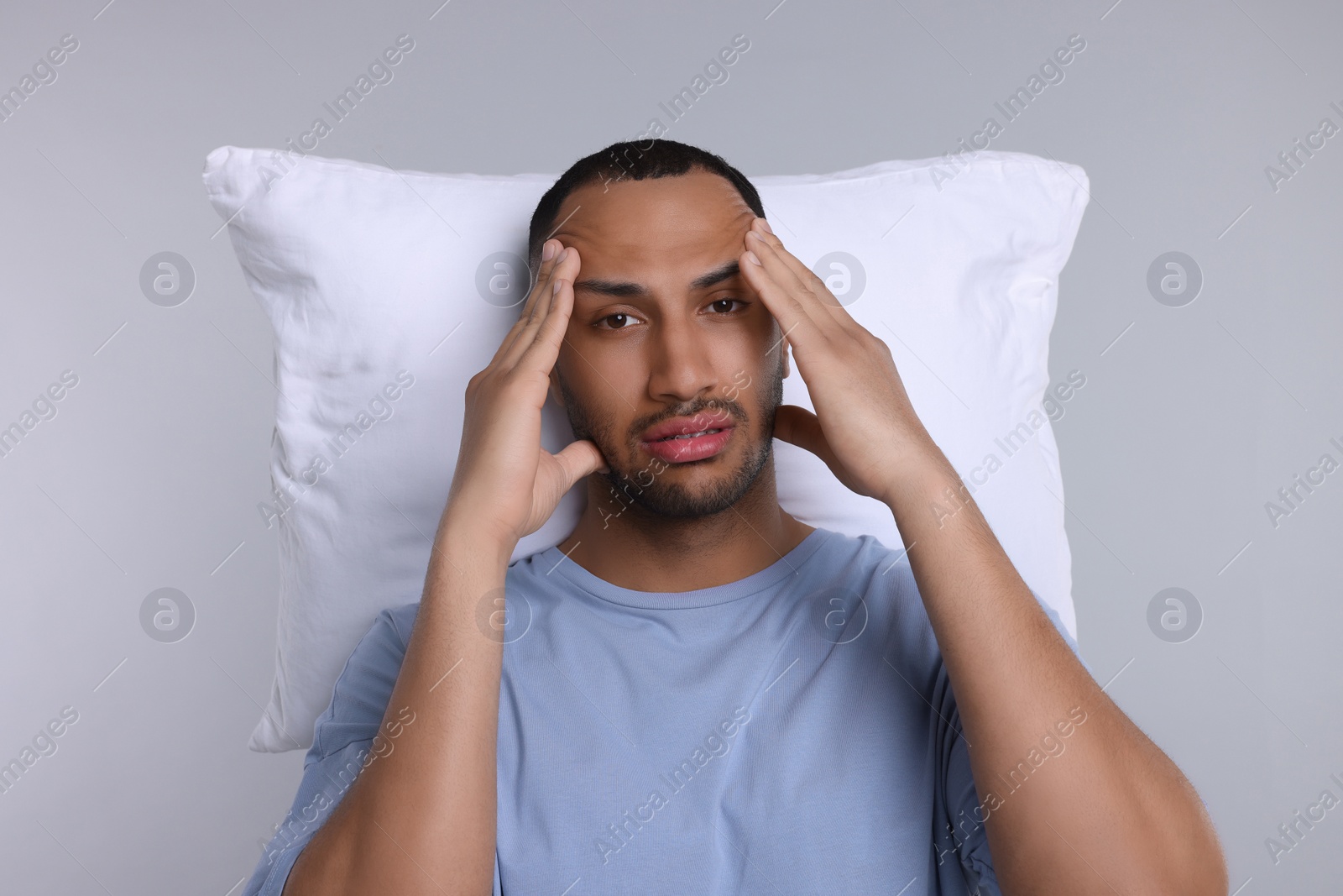 Photo of Tired man with pillow on light grey background. Insomnia problem