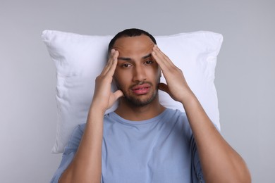 Photo of Tired man with pillow on light grey background. Insomnia problem