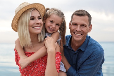 Happy family spending time together near sea on sunny summer day