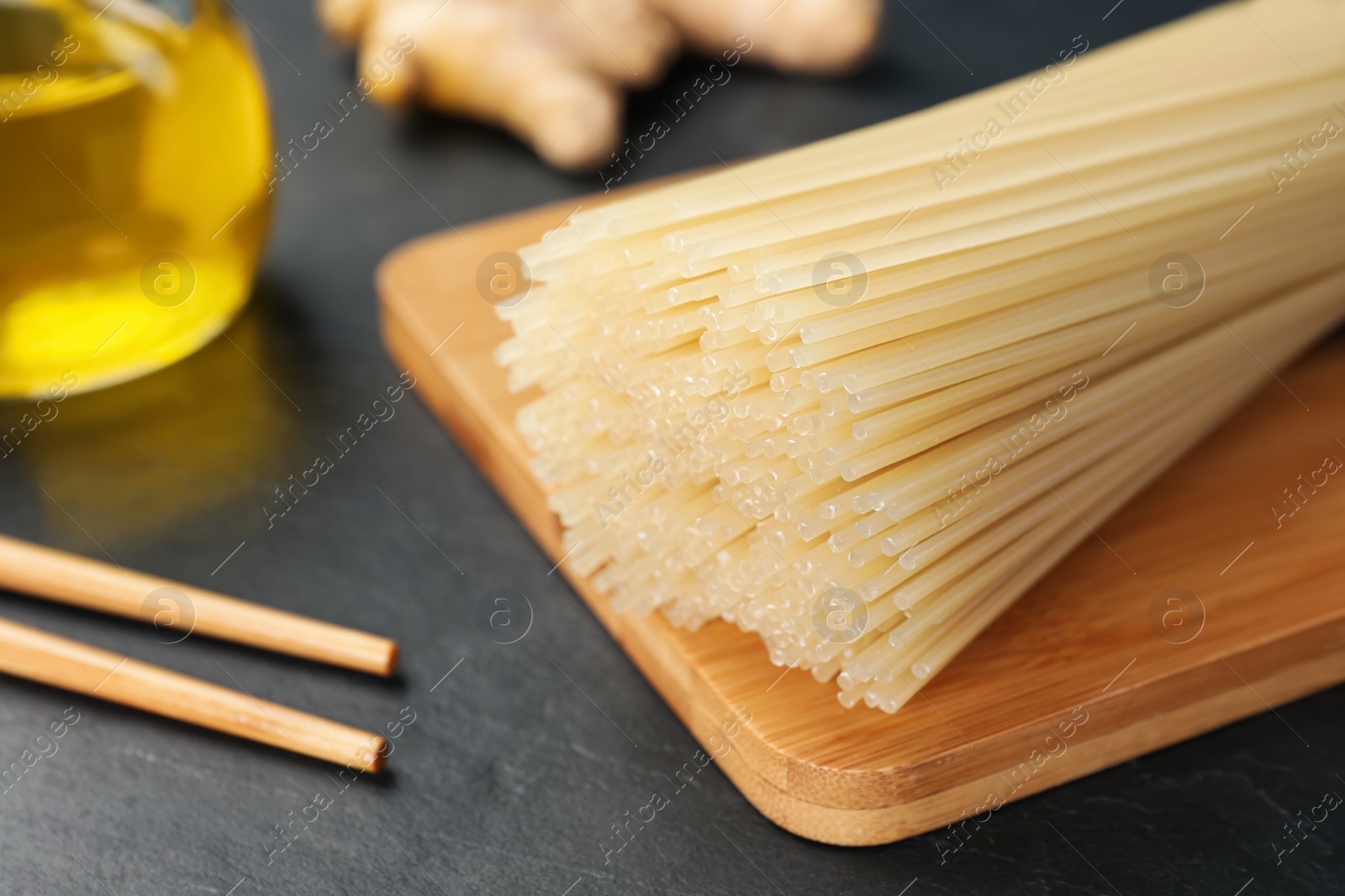 Photo of Dried rice noodles with chopsticks on black table, closeup