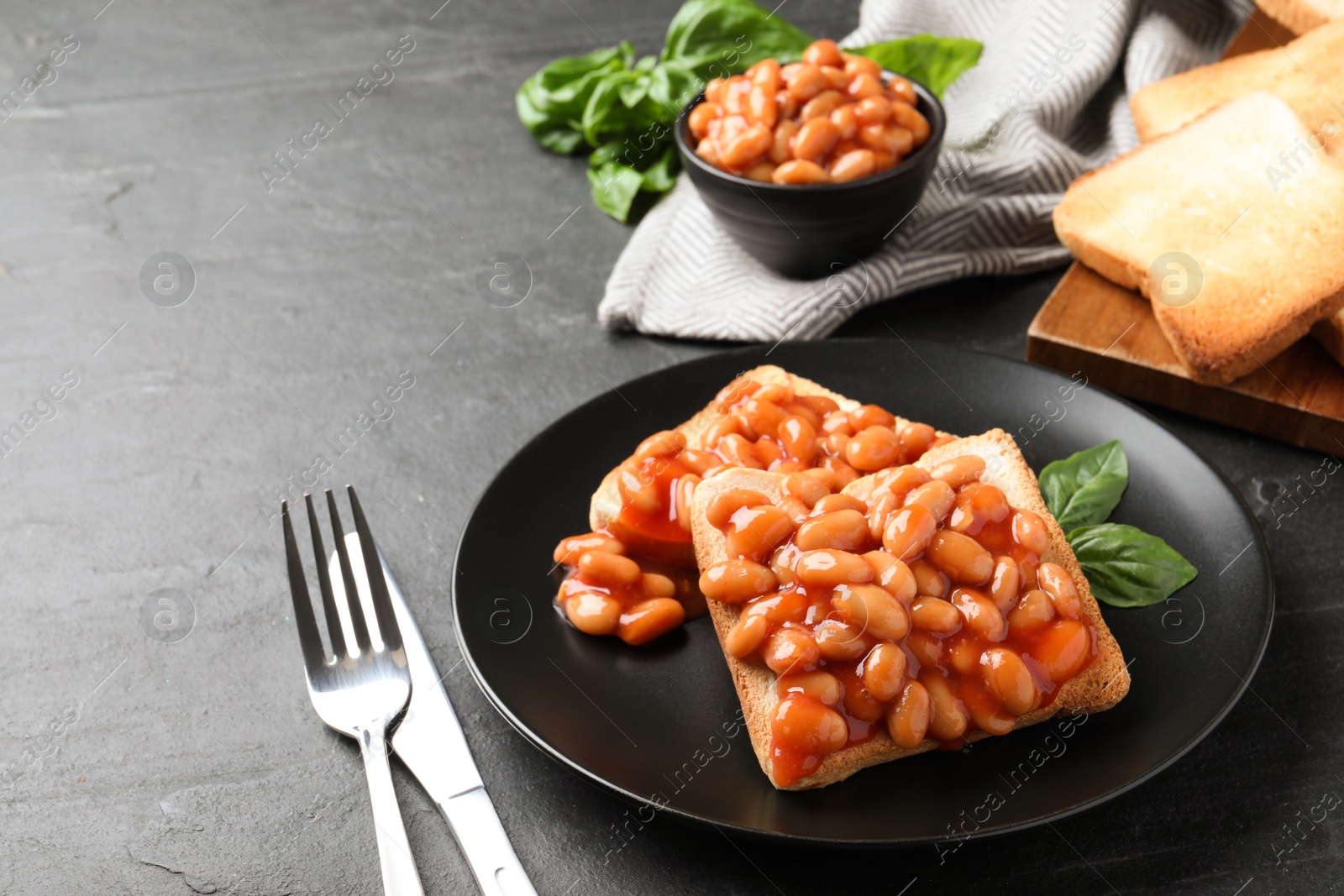 Photo of Toasts with delicious canned beans on black table