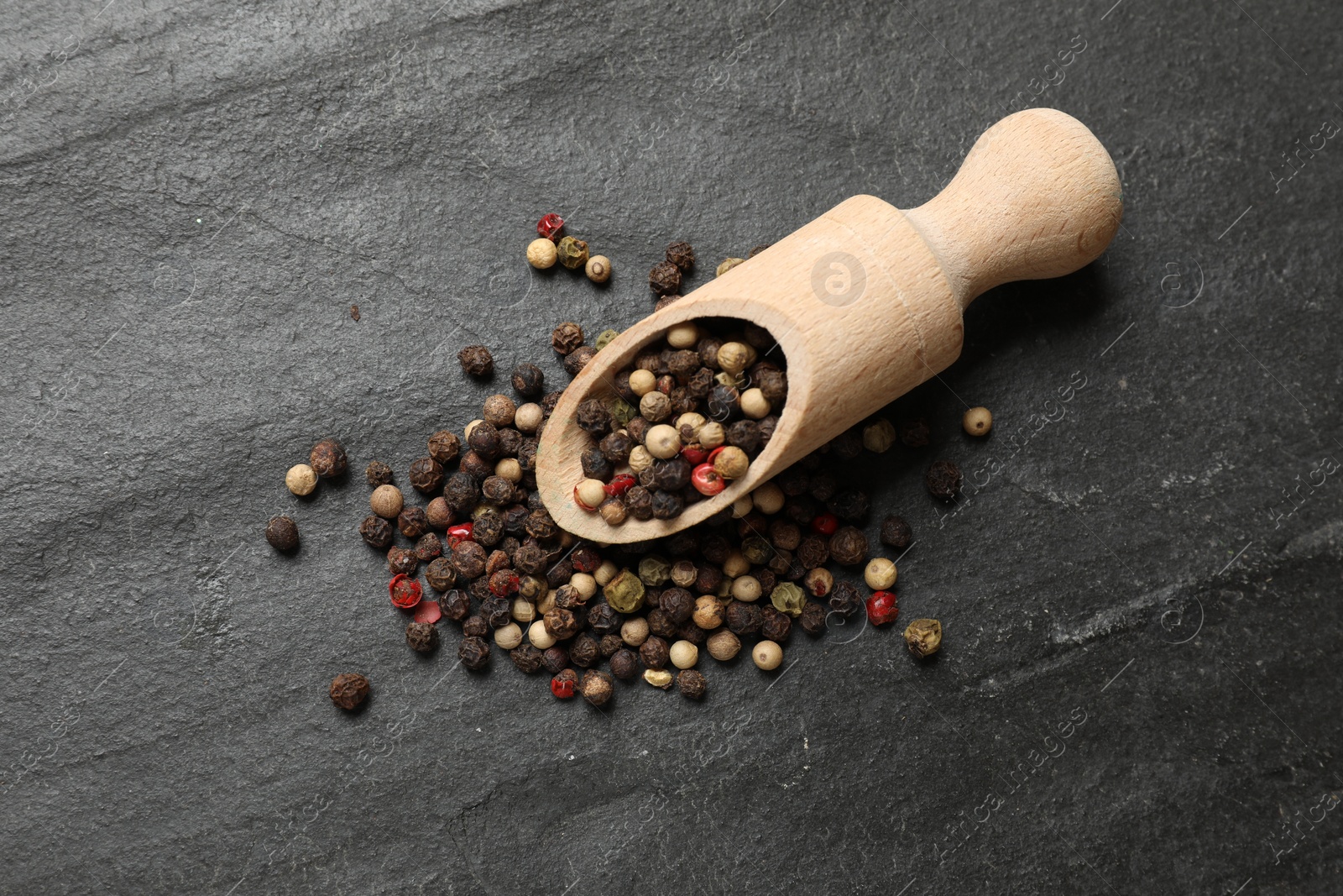 Photo of Aromatic spice. Different peppers in scoop on black table, top view