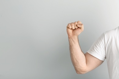 Photo of Young man showing clenched fist on light background. Space for text