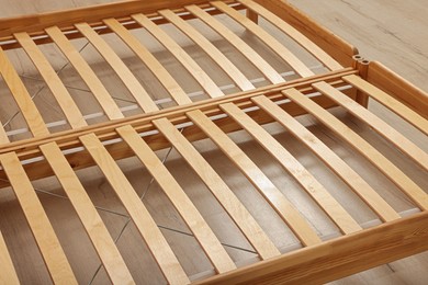 Photo of Wooden bed frame on floor, closeup view