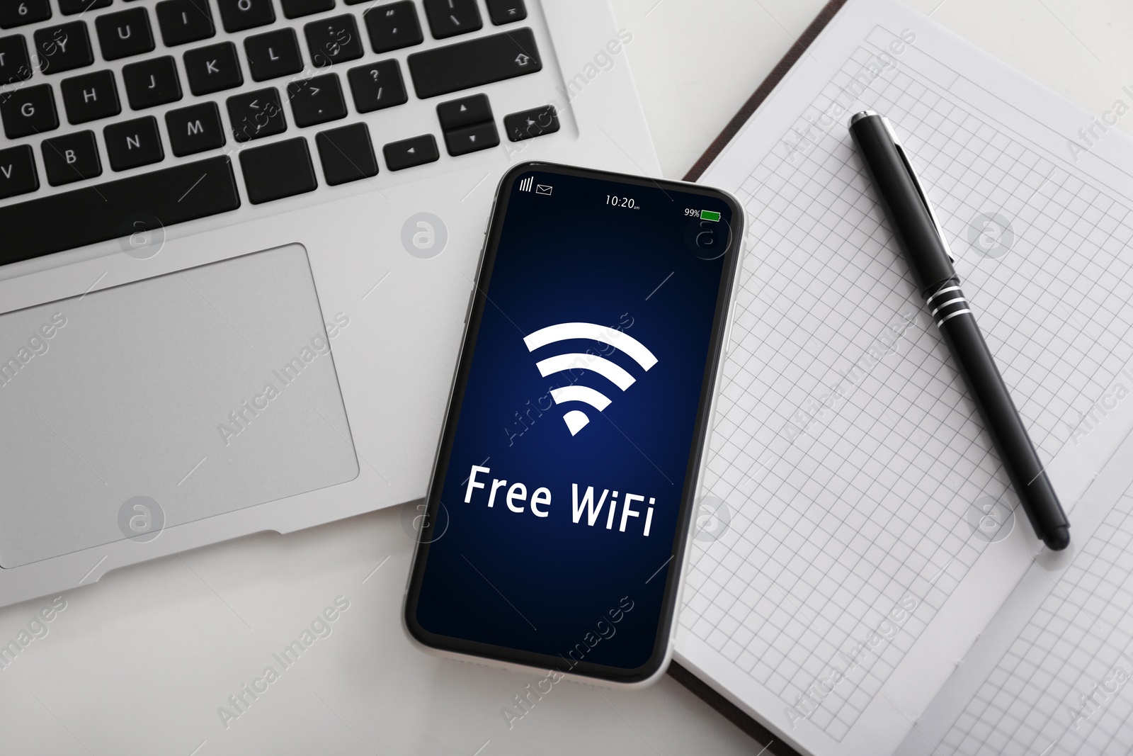 Image of Smartphone connected to WiFi on table with laptop and notepad on table, flat lay