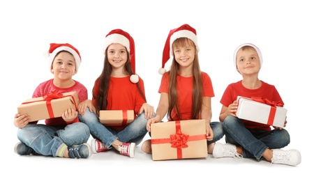 Cute little children in Santa hats with Christmas gifts on white background