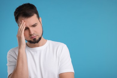 Portrait of sad man on light blue background, space for text