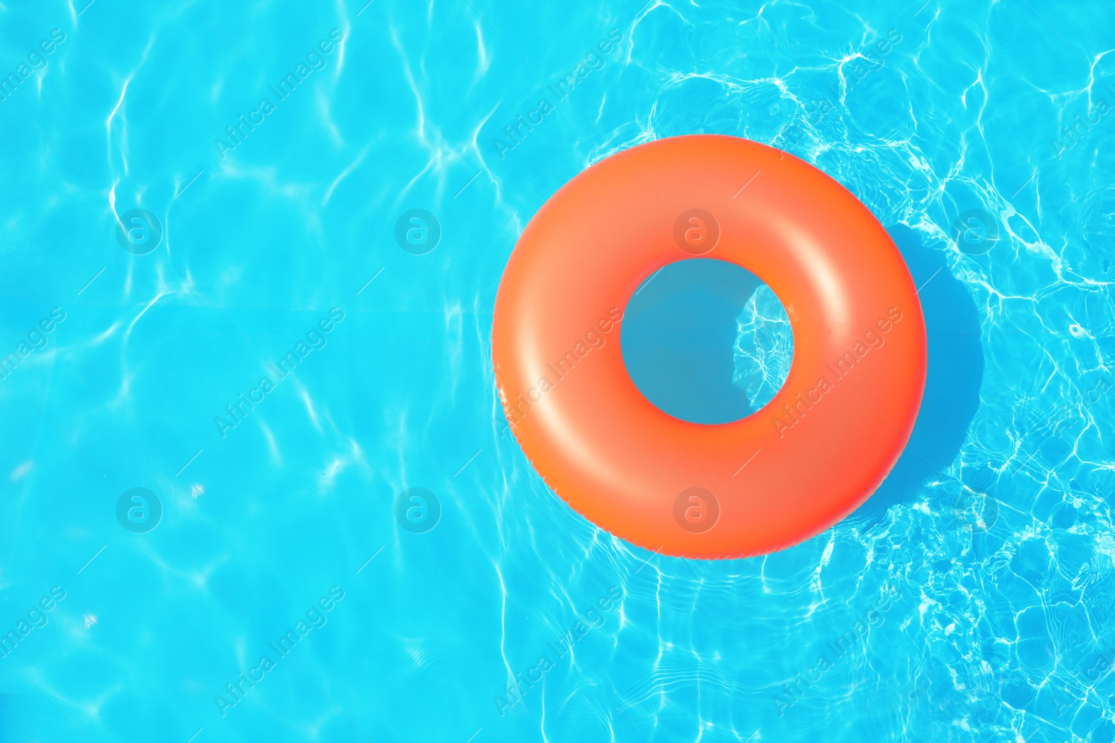 Photo of Inflatable ring floating in swimming pool on sunny day, top view with space for text