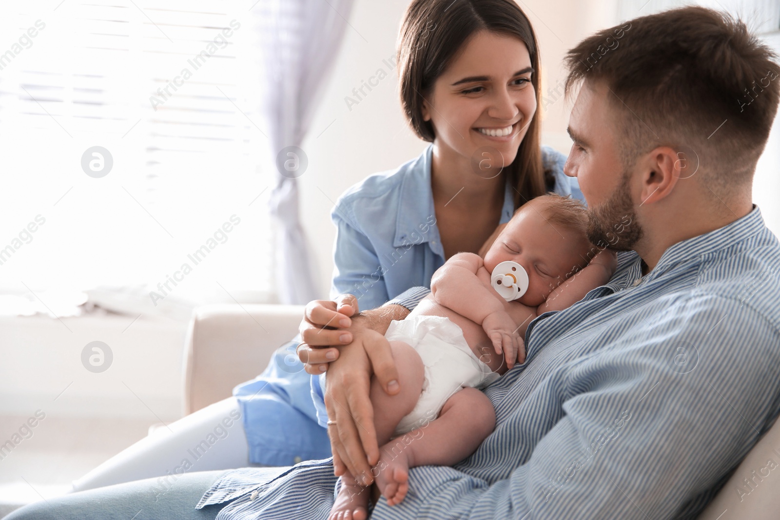 Photo of Happy couple with their newborn baby at home