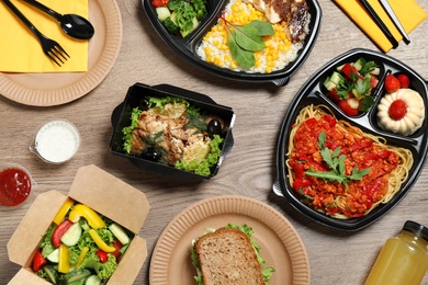 Photo of Lunchboxes with different meals on wooden table, flat lay. Healthy food delivery