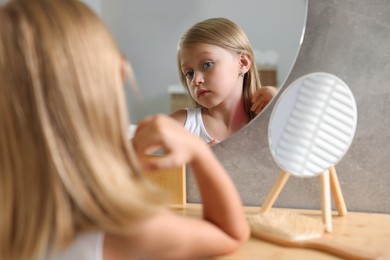Photo of Suffering from allergy. Little girl looking at her neck in mirror indoors