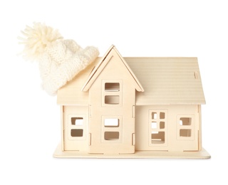 Photo of House model with knitted hat on roof against white background. Heating concept