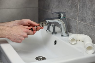 Plumber repairing metal faucet with spanner in bathroom, closeup