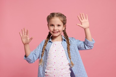 Photo of Happy girl giving high five with both hands on pink background