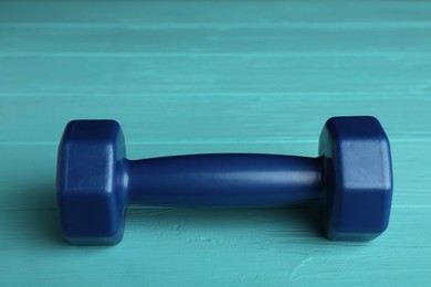 Photo of Blue vinyl dumbbell on turquoise wooden table