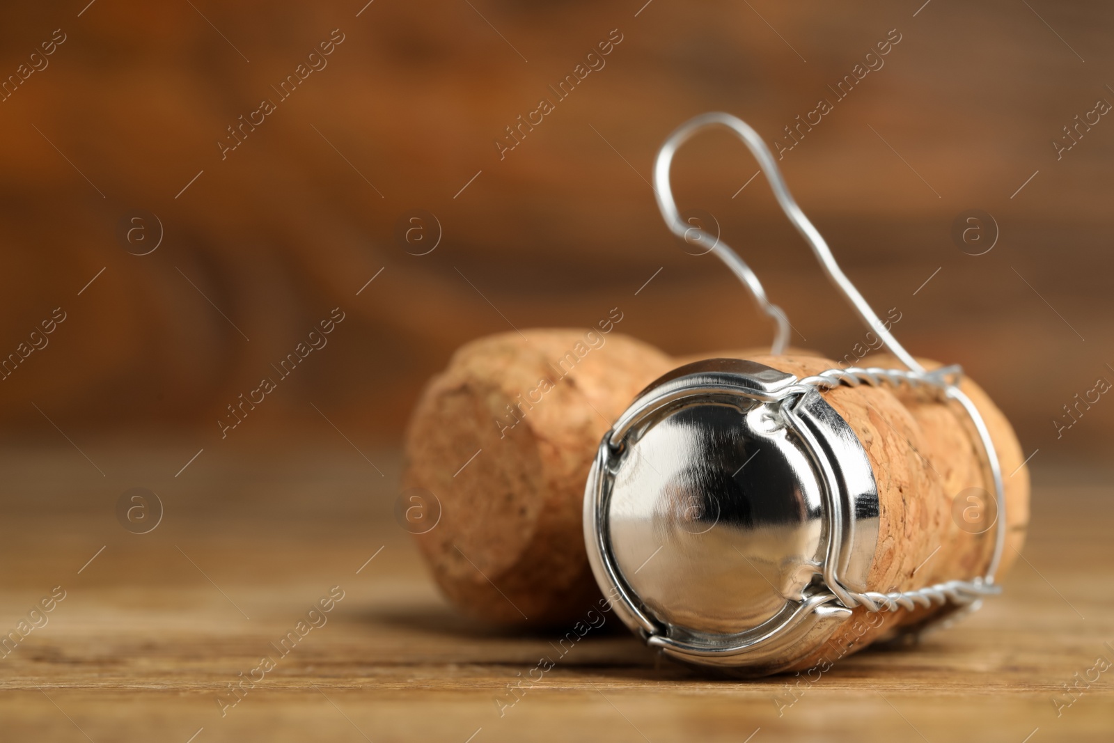 Photo of Sparkling wine corks with muselet cap on wooden table, closeup. Space for text