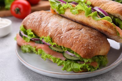 Photo of Delicious sandwiches with fresh vegetables and salmon on light gray table, closeup