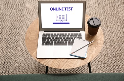 Photo of Laptop with online test on wooden table indoors