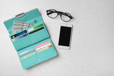 Photo of Smartphone, glasses and stylish wallet with cash and credit cards on light background, top view