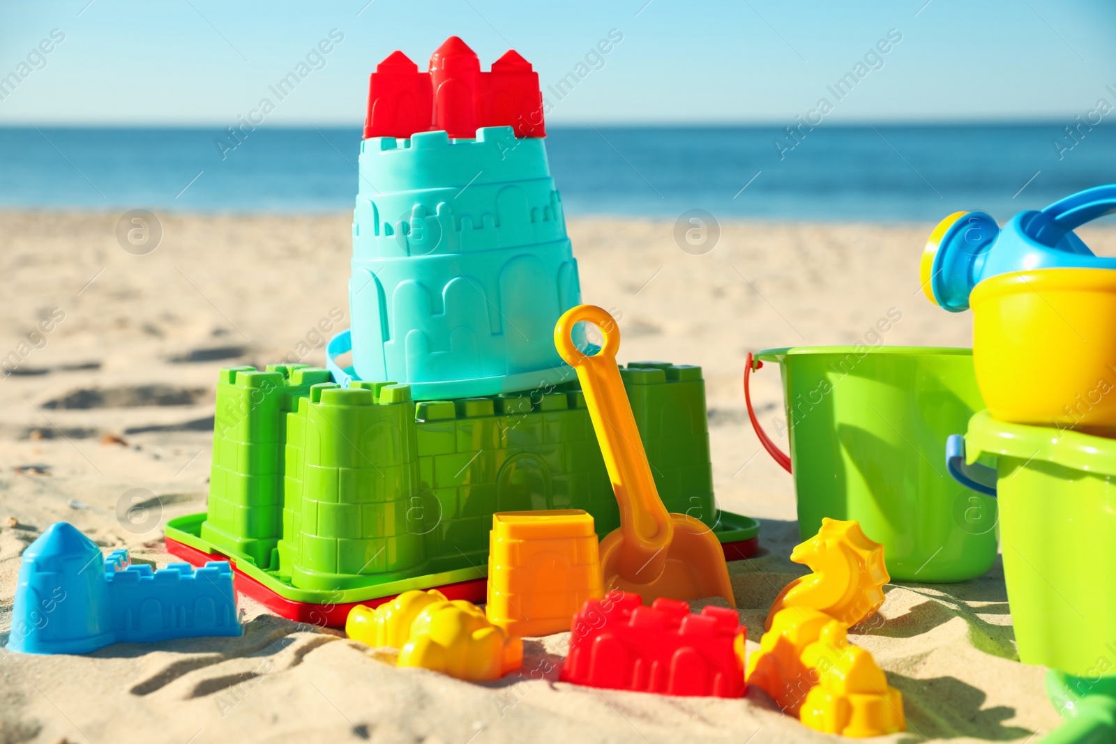 Photo of Different child plastic toys on sandy beach, closeup