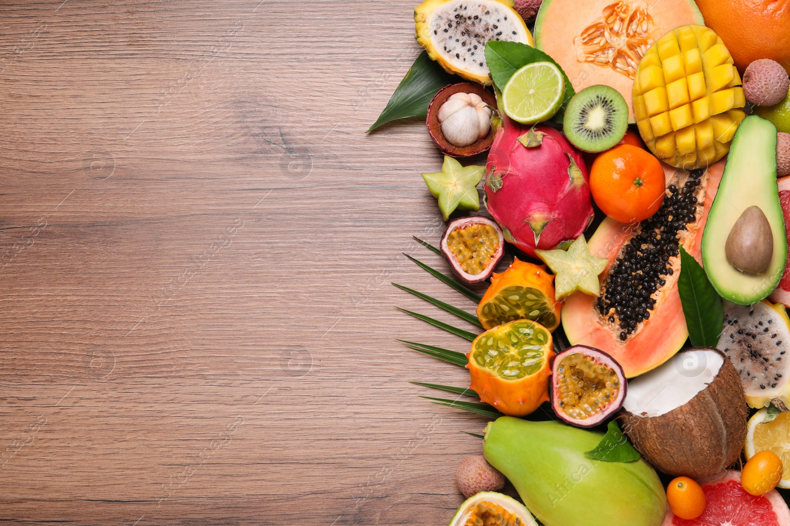 Photo of Different exotic fruits on wooden table, flat lay. Space for text