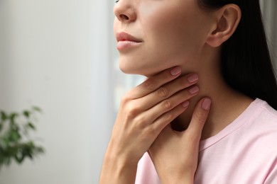 Photo of Young woman doing thyroid self examination indoors, closeup. Space for text